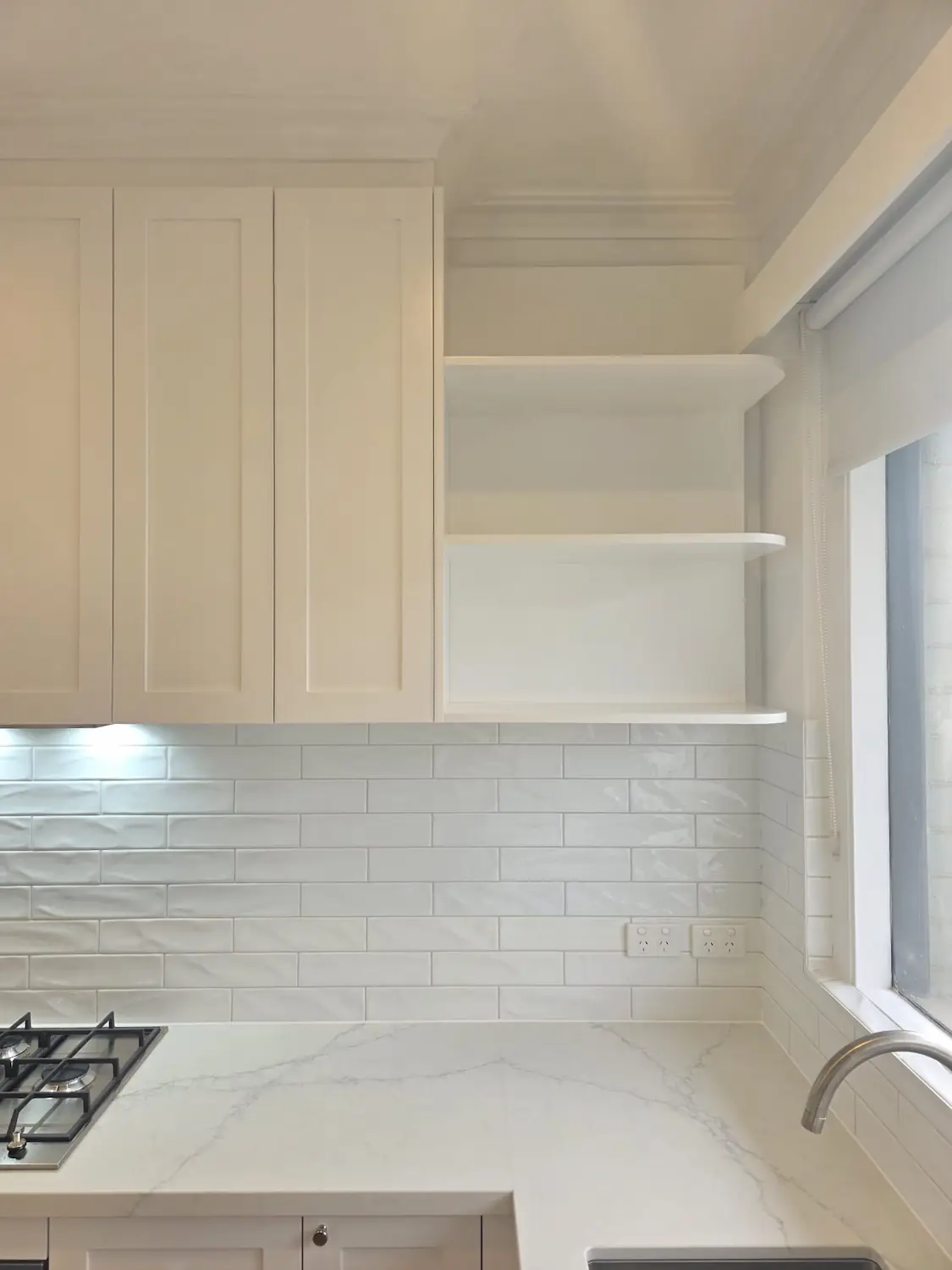 AC Stone Allure Blue benchtop with two pack shaker cabinets, subway tile splashback and open corner shelving in an East Melbourne kitchen by Northside Joinery Melbourne