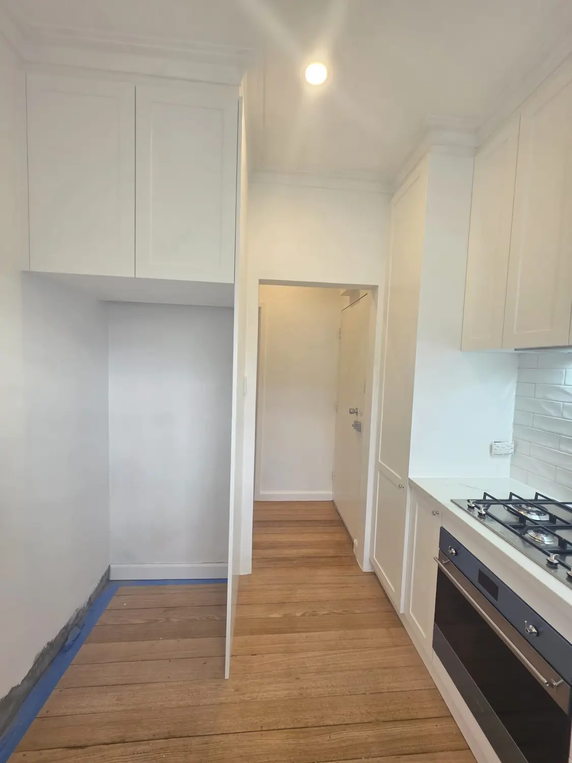 Narrow galley custom kitchen in East Melbourne with two pack shaker joinery taken to the cornice line and full height cabinetry by Northside Joinery Melbourne