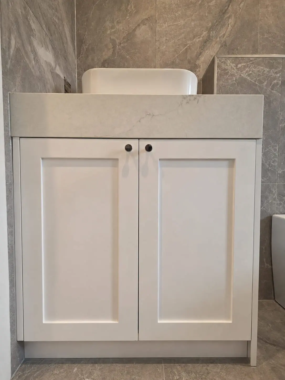 Custom white shaker bathroom vanity with stone top against grey tiling in an East Melbourne apartment by Northside Joinery Melbourne