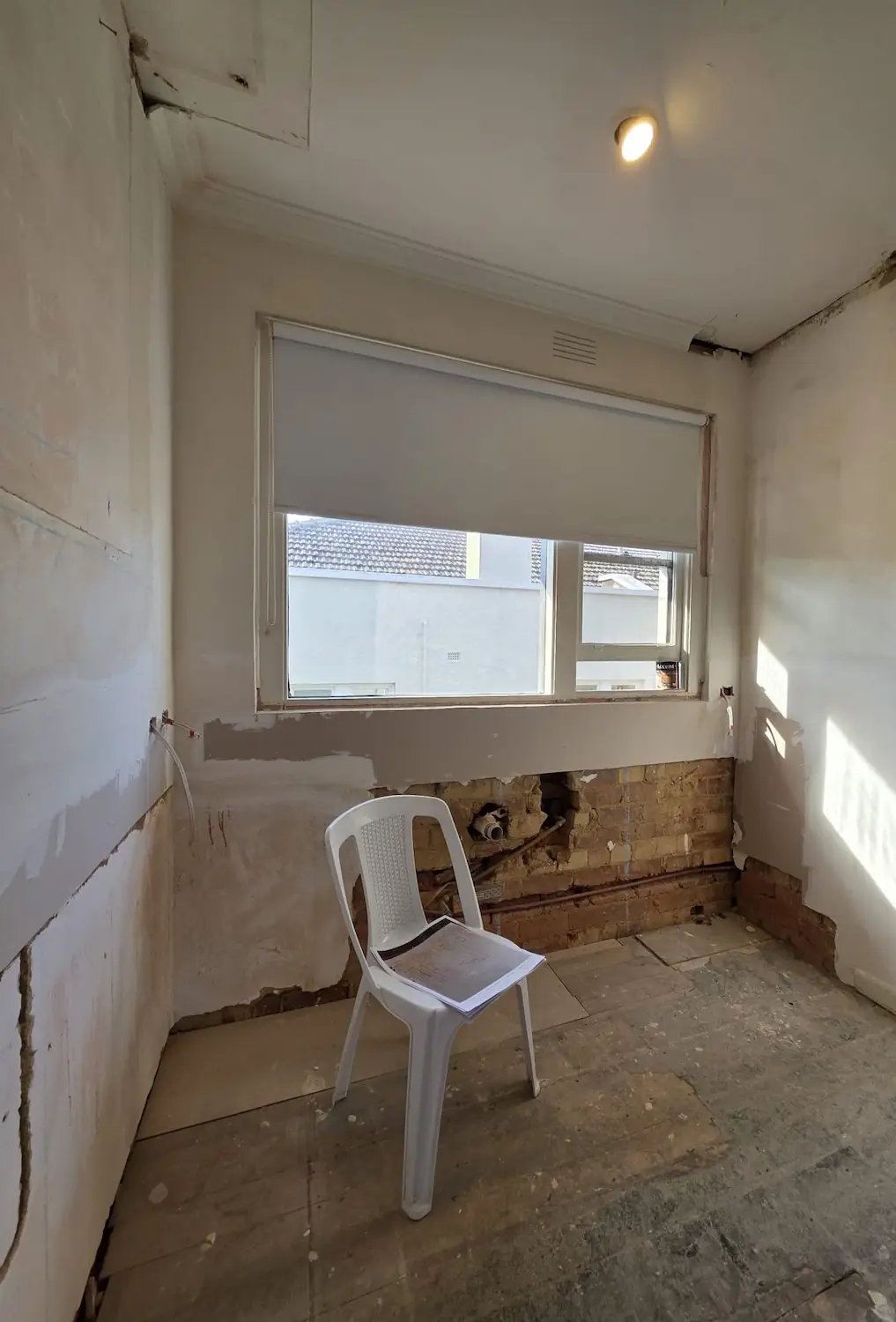 Kitchen and laundry area during demolition in an East Melbourne apartment showing exposed brick and original timber floor before custom joinery by Northside Joinery Melbourne